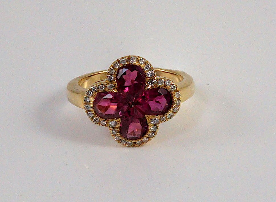 A modern 18k gold four stone pear shaped pink tourmaline set dress ring with diamond chip set border